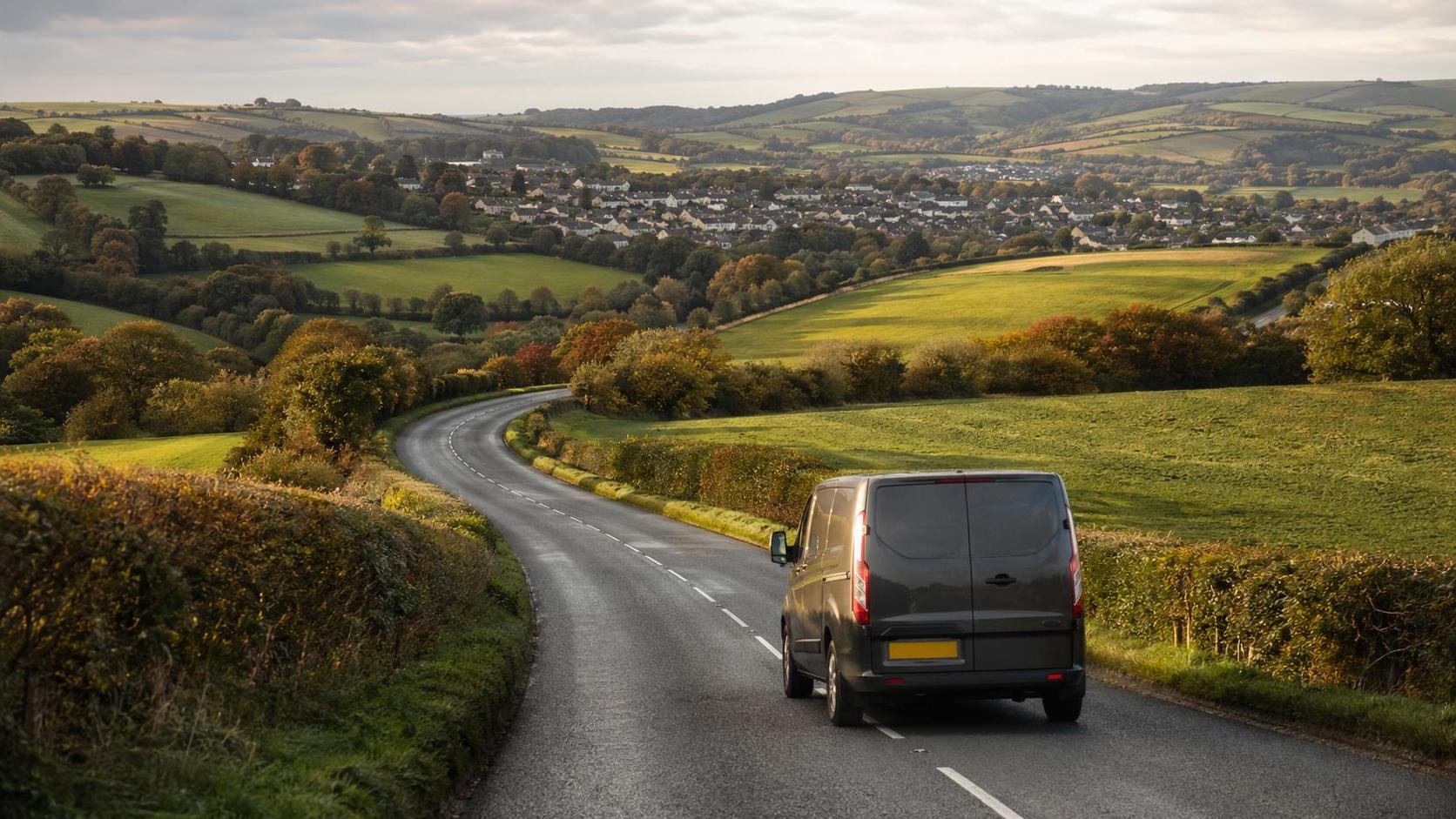 Curving valley road near Liskeard with hedged fields in warm early autumn light
